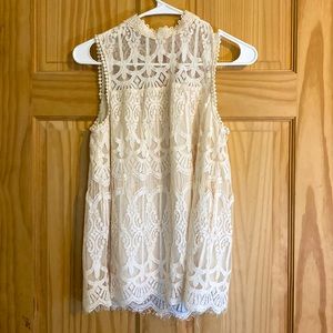A XS lacy white top with no sleeves and has a silky like under top.